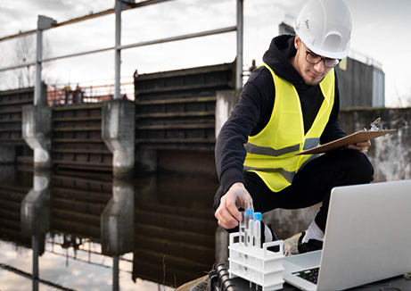 wellness water company - a man in a safety vest is working on a laptop