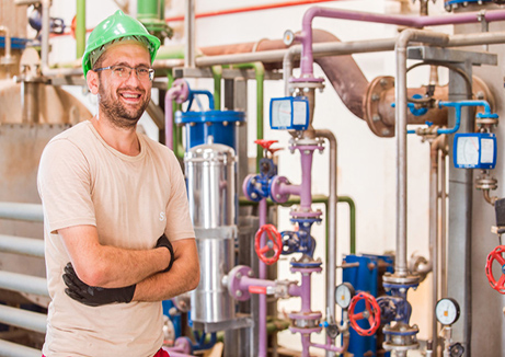 wellness water company - a man in a green hat standing in front of pipes