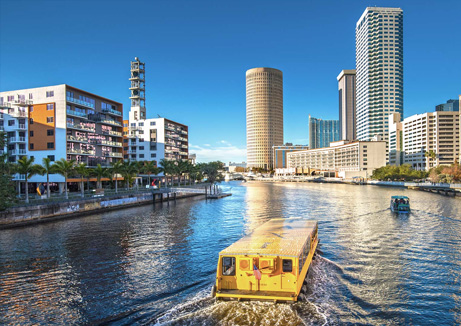 wellness water company - a yellow boat traveling down a river next to tall buildings