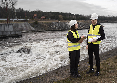 welness water company - a person and person in safety vests and helmets standing next to a river